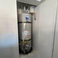 Water heater in a utility closet with pipes, valve, and warning labels.