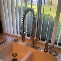 Kitchen sink with a high-arc spring faucet beside a window with vertical blinds.