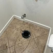 Bathroom floor with a toilet drain opening and a wall plumbing stub-out.