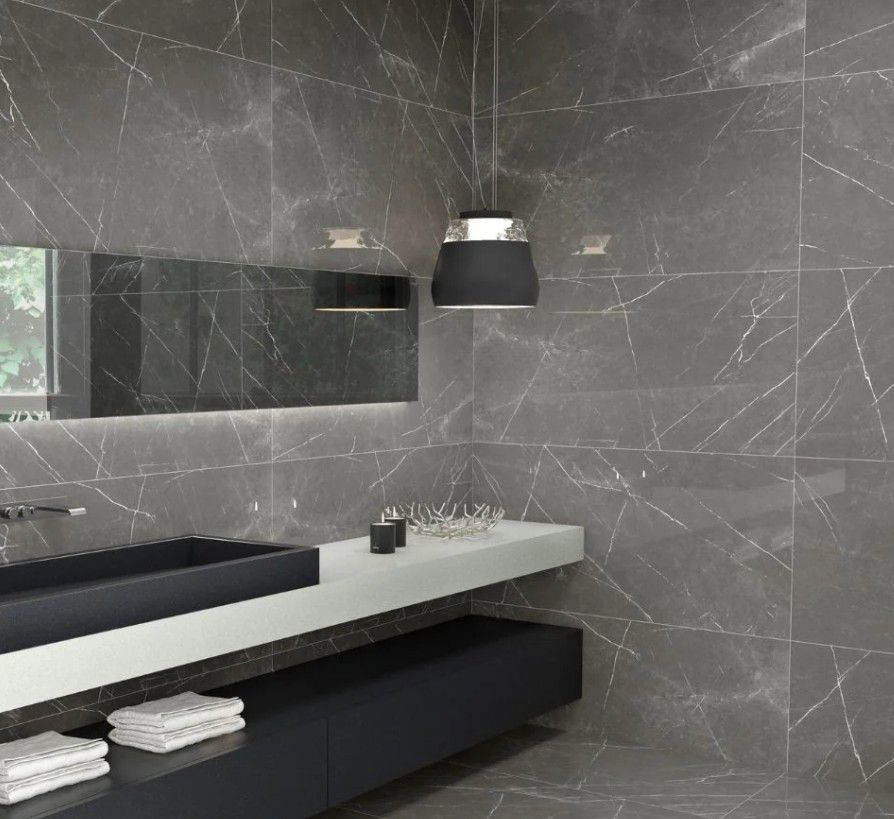 A bathroom with gray tiles and a black sink