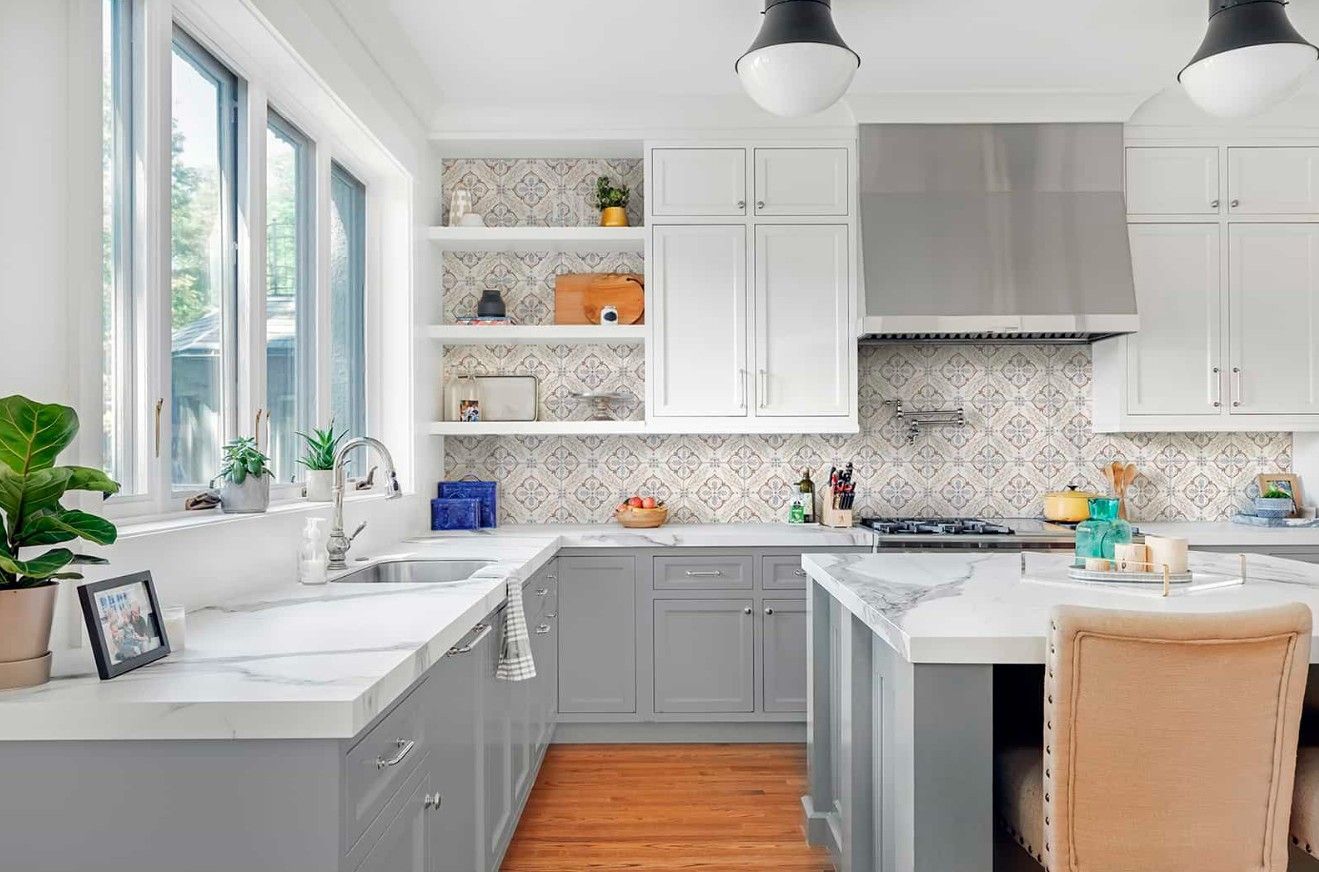 A kitchen with gray cabinets , white counter tops , a sink , and a stove.