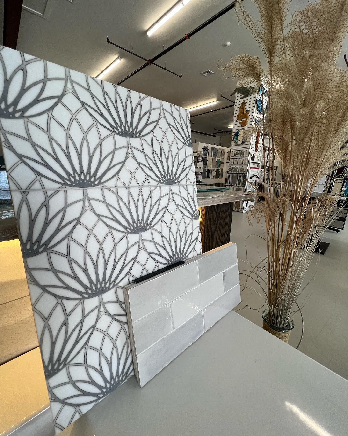 A white tile with a floral pattern is sitting on a counter in a store.