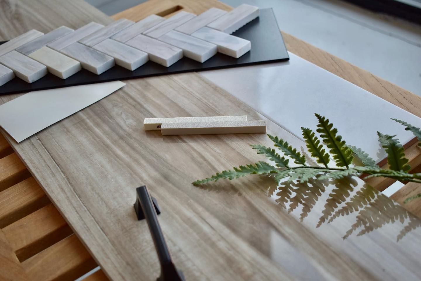 A wooden cutting board with a fern on top of it.