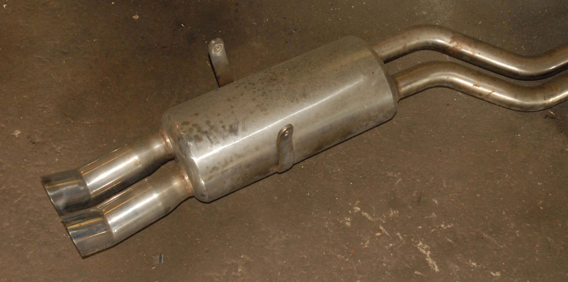 Dual-outlet car exhaust muffler. Metallic finish.