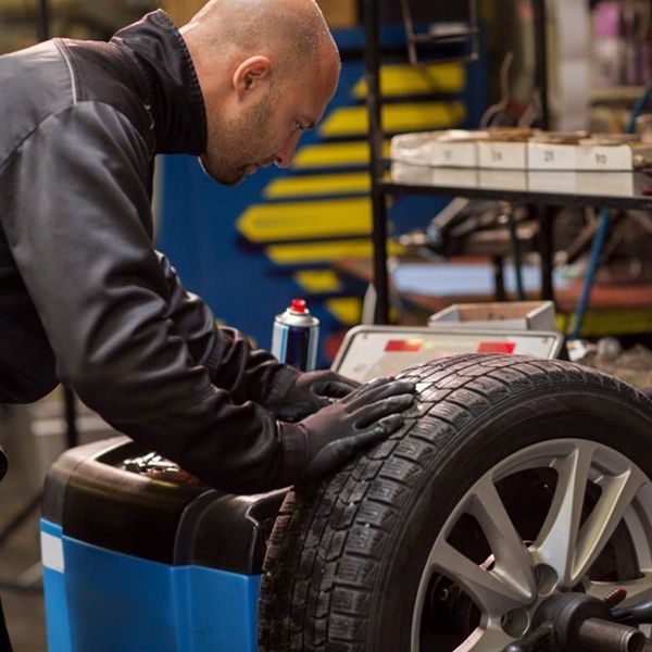 Mechanic balancing a tire on a machine in a garage.