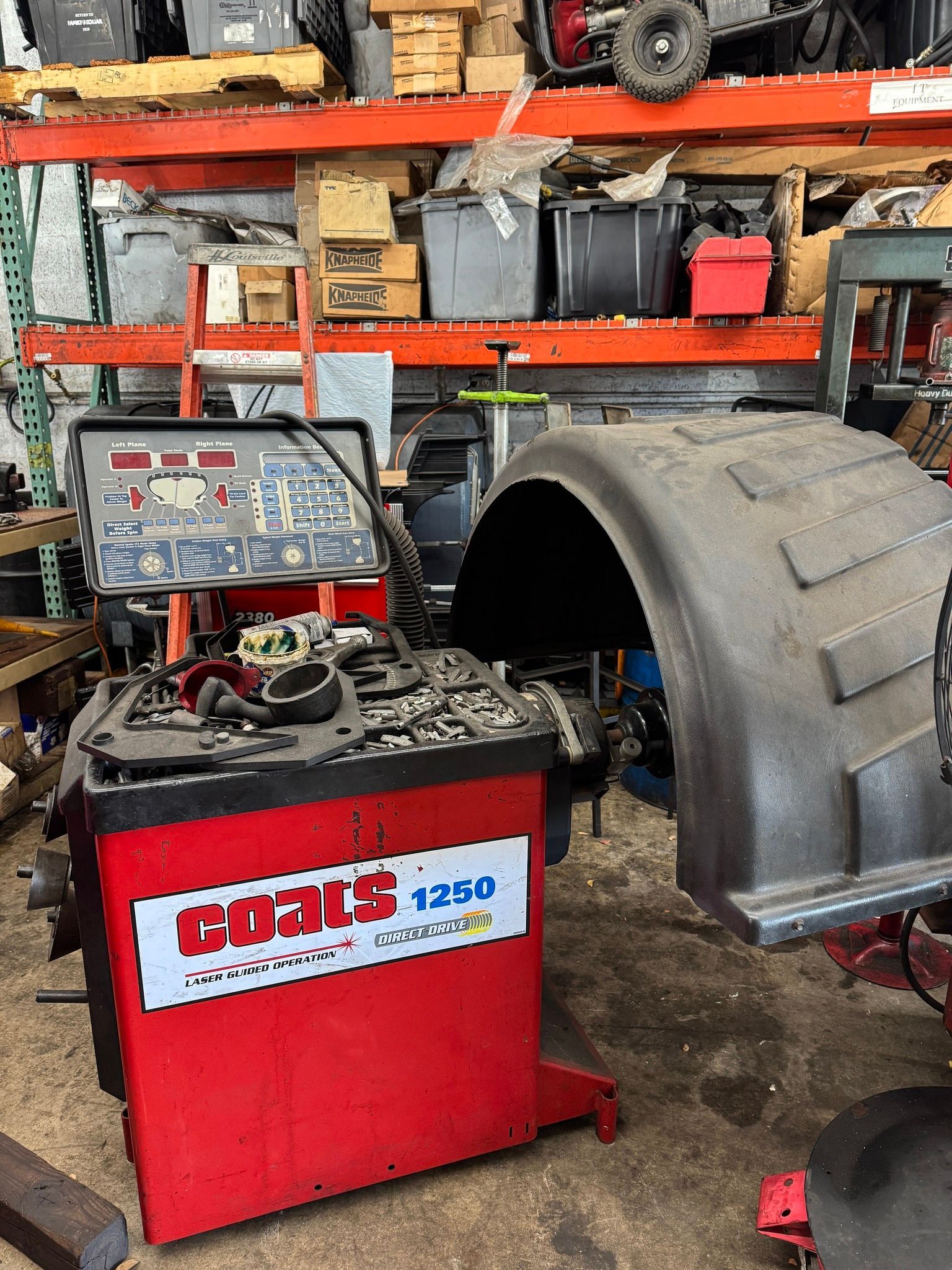 A red Coats 125D tire balancing machine in a cluttered auto shop.