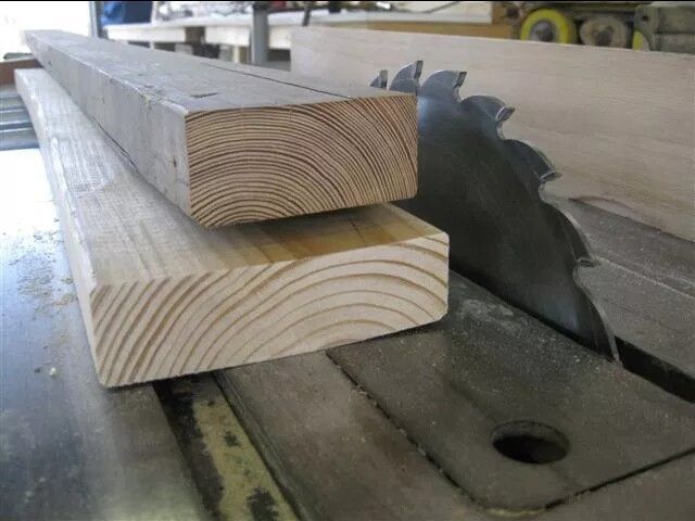 Wood planks on a table saw, with a blade ready to cut the wood.