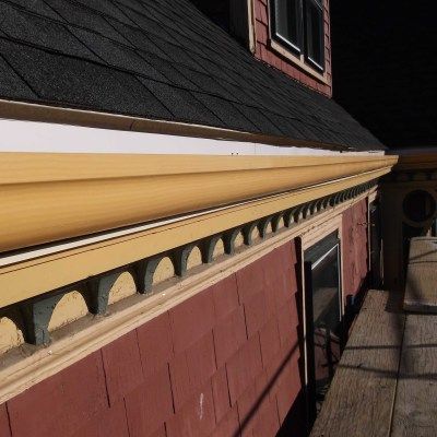Red and yellow exterior wall detail with decorative molding and dark roof.