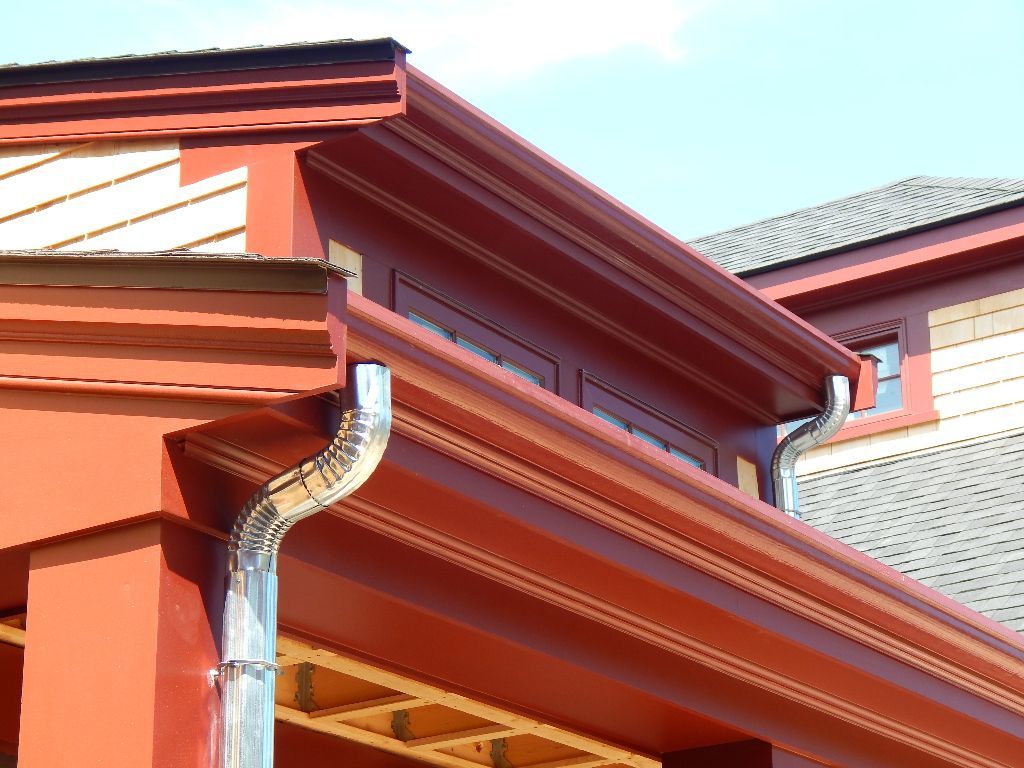 Red house with a shiny metal gutter and downspout.