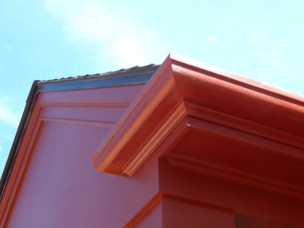 Orange trim on a pink building against a blue sky.