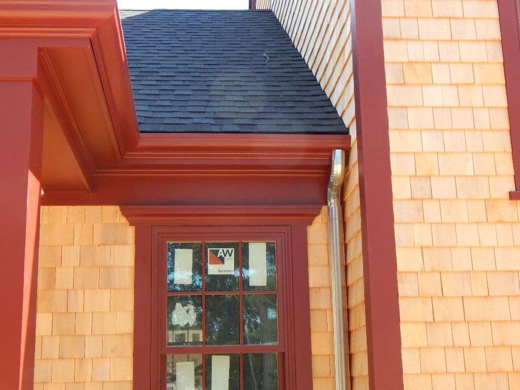 Red-trimmed window and roofline on a wood-shingled building, with a silver gutter.