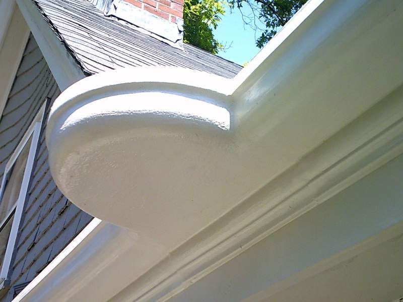 White gutter system on a house, with rounded corner and visible roofline.
