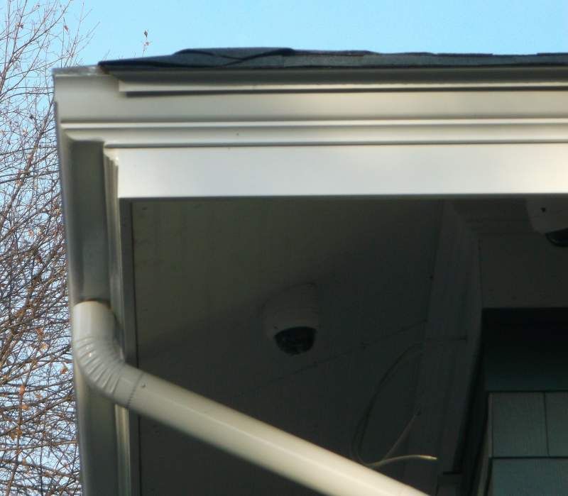 White guttering and trim on a house, with a security camera mounted underneath.