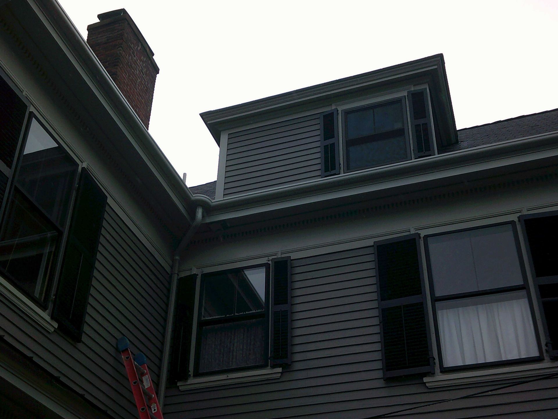 Gray house exterior with shutters and a dormer.