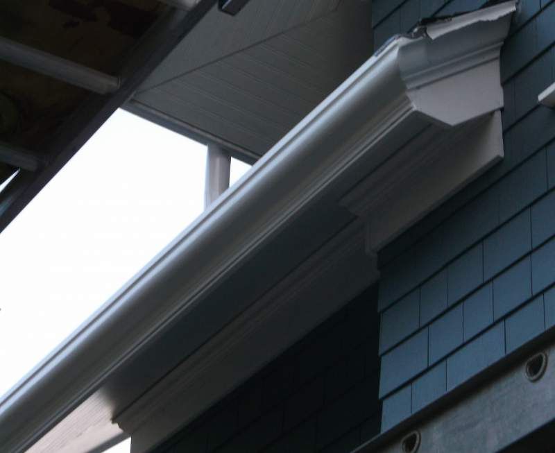 White gutter and trim attached to a blue shingled house.