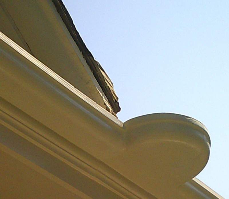 Beige gutter and roofline against a clear blue sky.