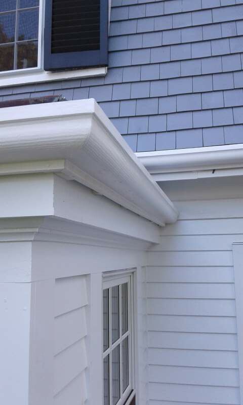 White gutter on a house with blue shingles and white siding.