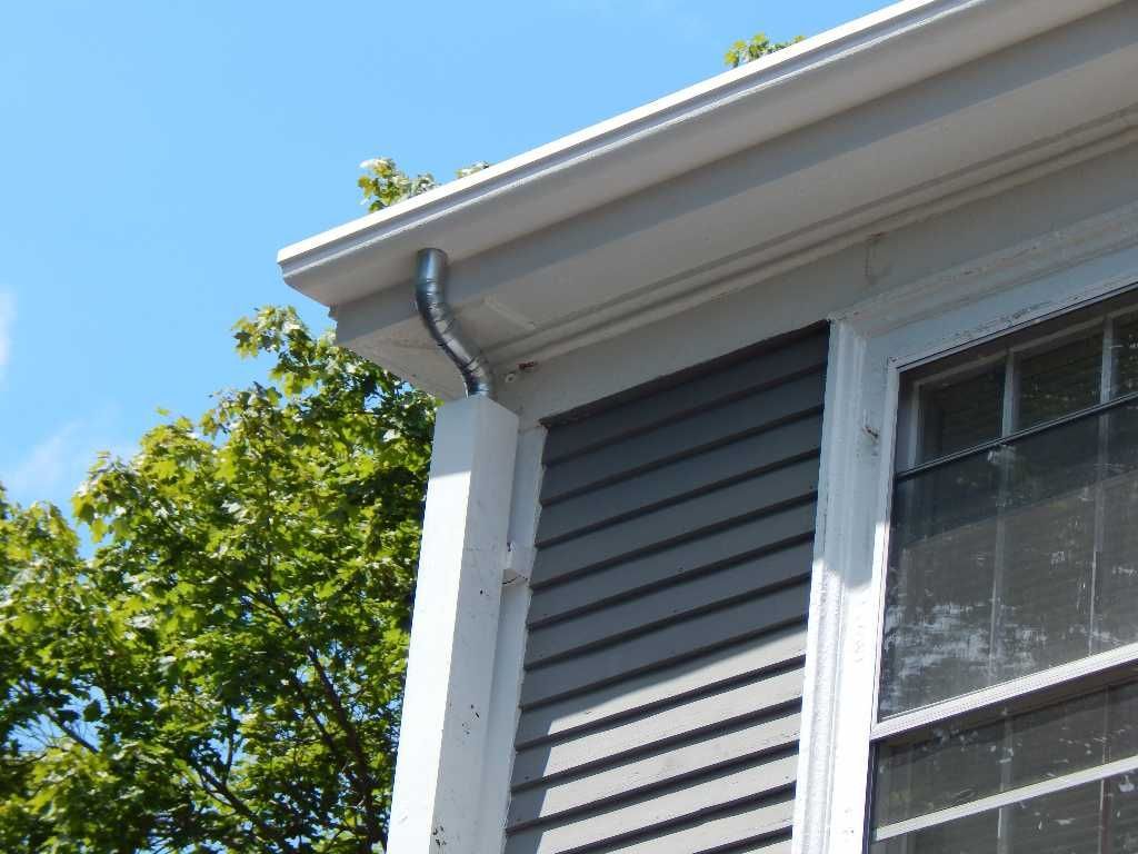 Grey siding with white trim and a curved gutter. A tree is in the background.