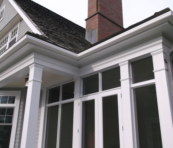 White house exterior with large windows, columns, and a brick chimney.