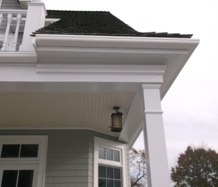 White trim detail on a house with dark roof and porch column.