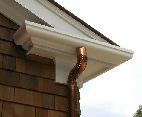 Copper rain gutter on a white soffit and brown shingle siding.