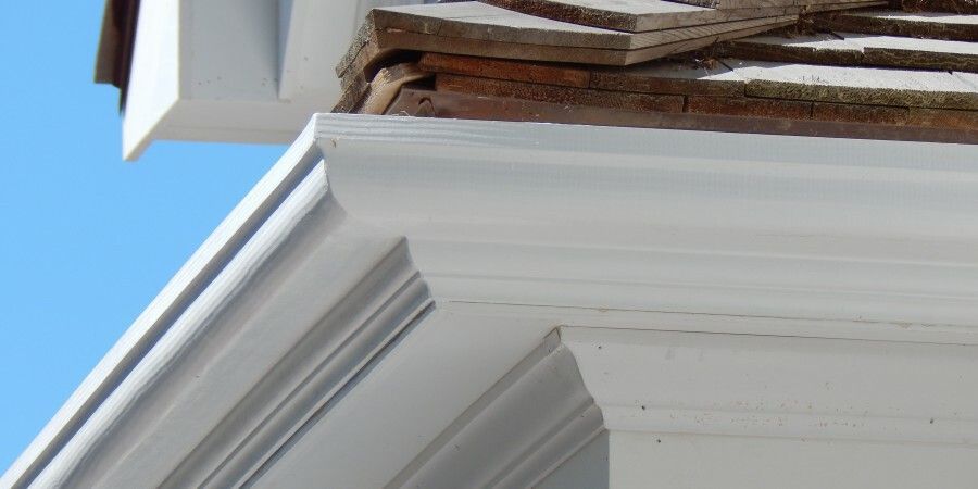 White trim and roof eaves against a blue sky, details of a building's exterior.