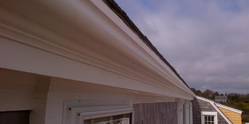 Exterior view of a white building with detailed trim and a cloudy sky.