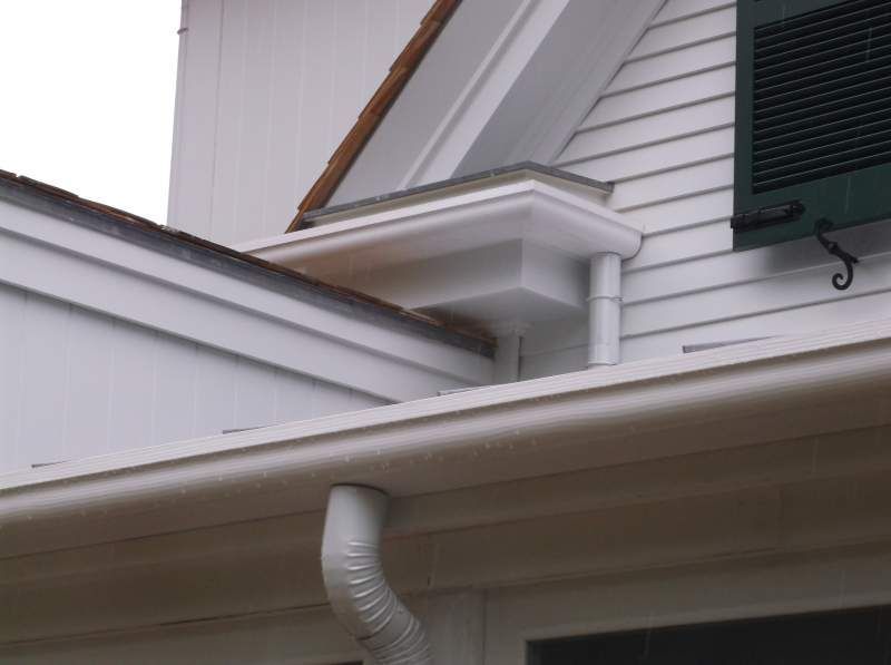 White house exterior with gutters, downspout, and decorative trim.