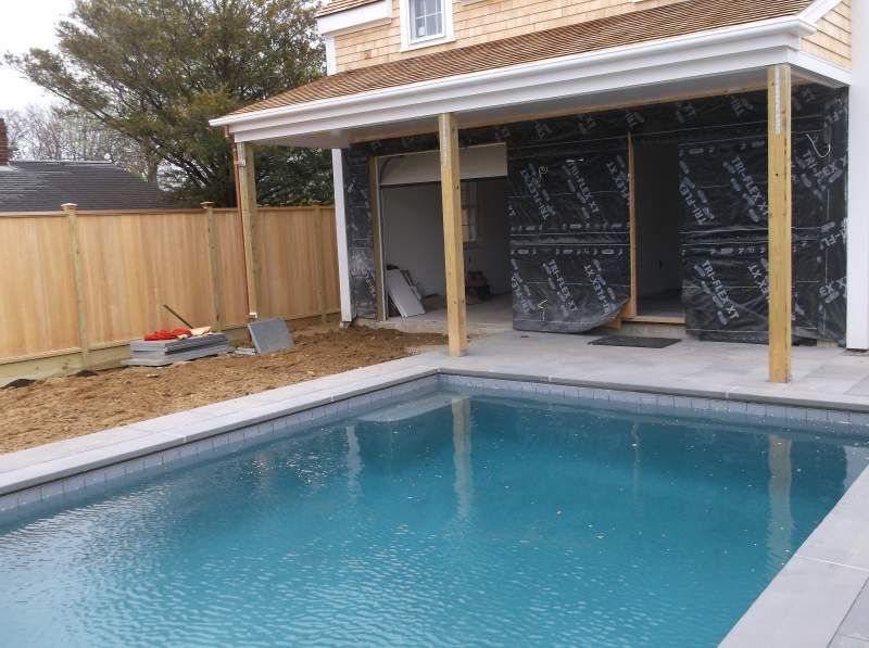 Pool with unfinished building; construction materials and wood framing; blue water, brown wood.
