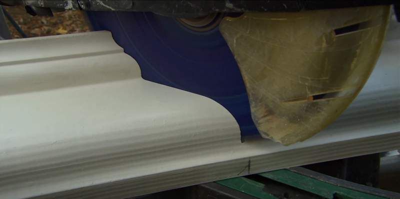 A saw blade cutting a decorative wooden molding.