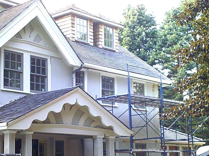 Two-story house with light-colored siding, a dark roof, and scaffolding for construction.