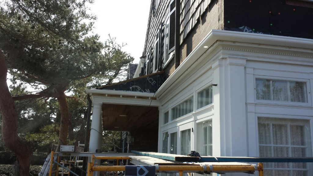House exterior with white trim, brown shingles, and a visible construction scaffold.