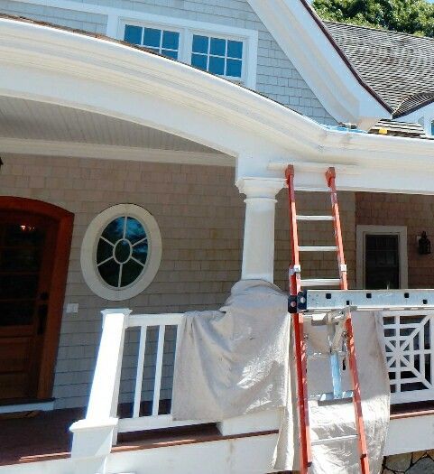 Exterior of house under construction with a ladder and scaffolding next to a white column.