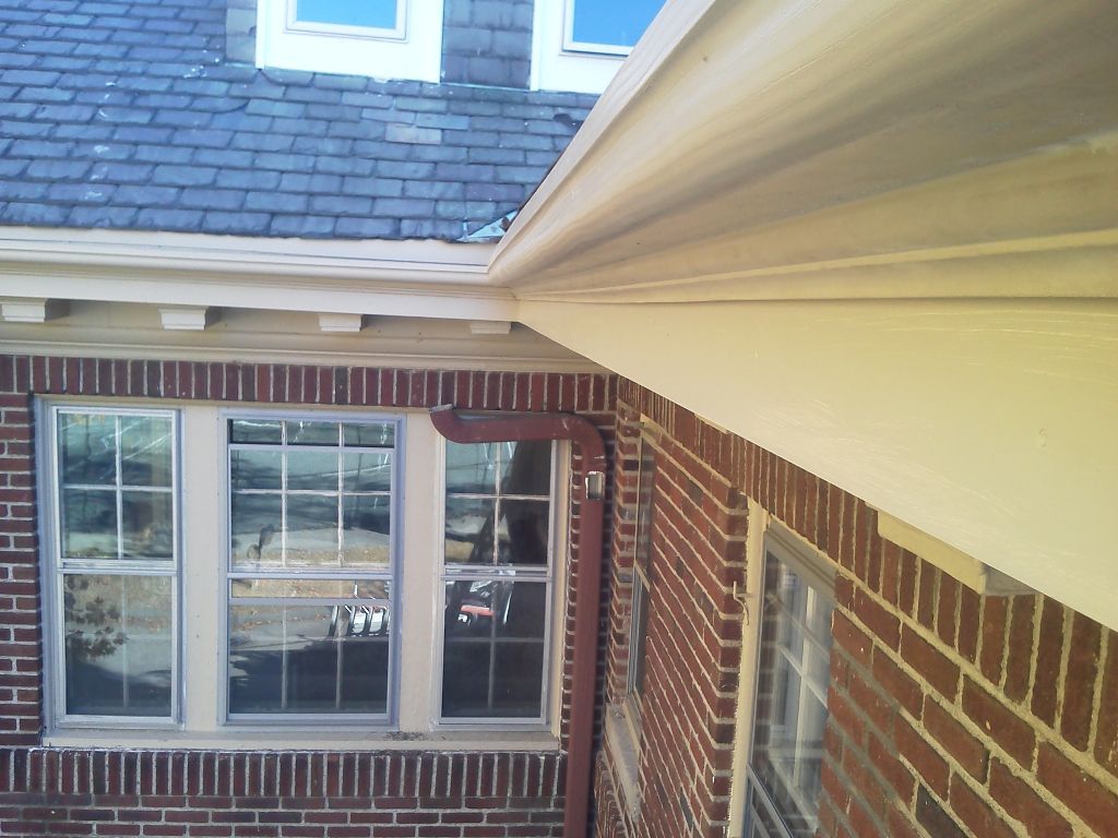 Exterior brick wall with windows, a roof, and white trim.