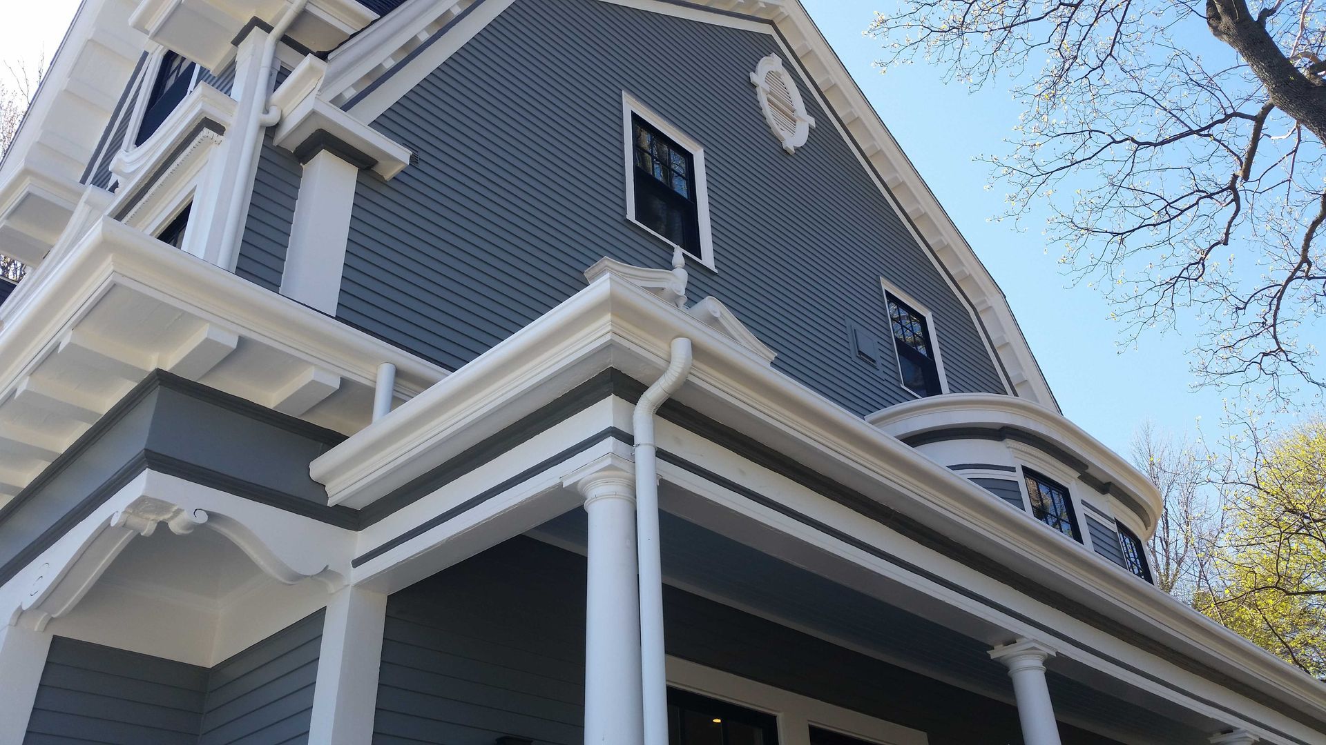 Blue and white house exterior with porch and decorative trim, under a sunny sky.