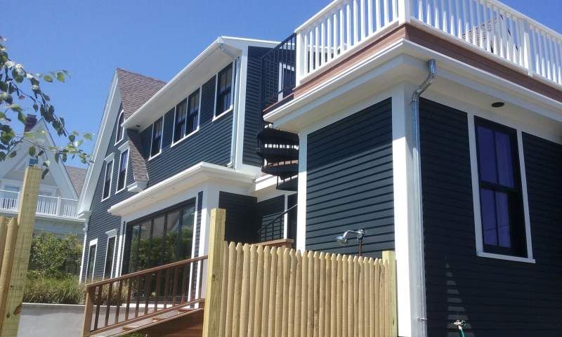 Dark blue house with white trim, spiral staircase, and wooden deck.