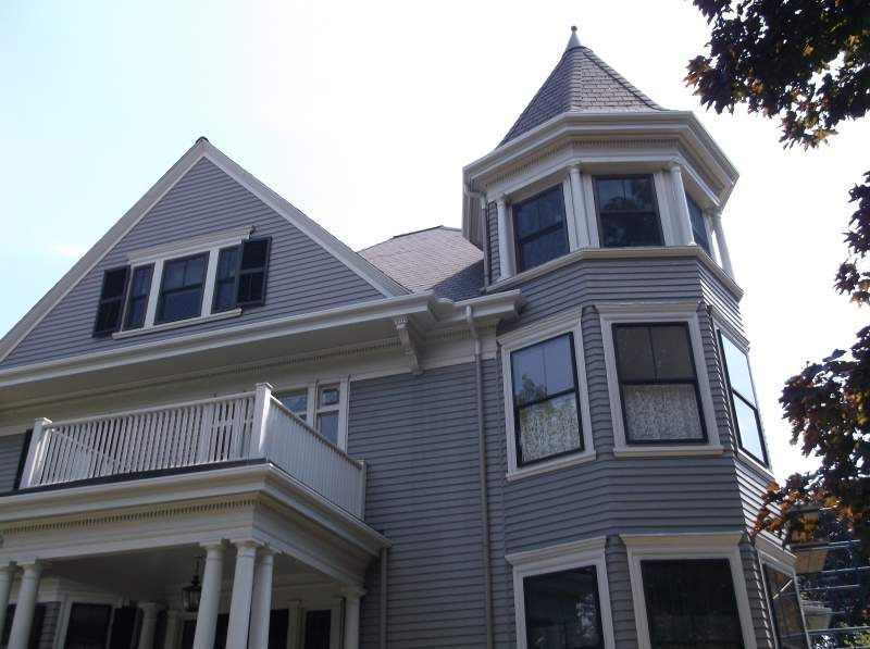 Gray Victorian house with a turret and white porch.