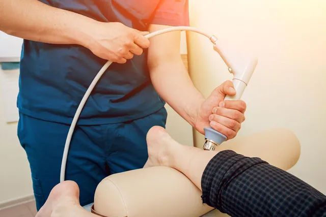 A doctor is using a machine on a patient 's leg.