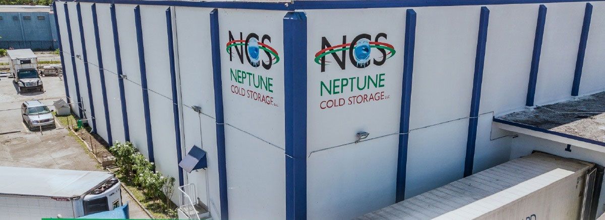 Exterior view of a Neptune Cold Storage facility with the company's logo visible on the building. Cars are parked nearby.