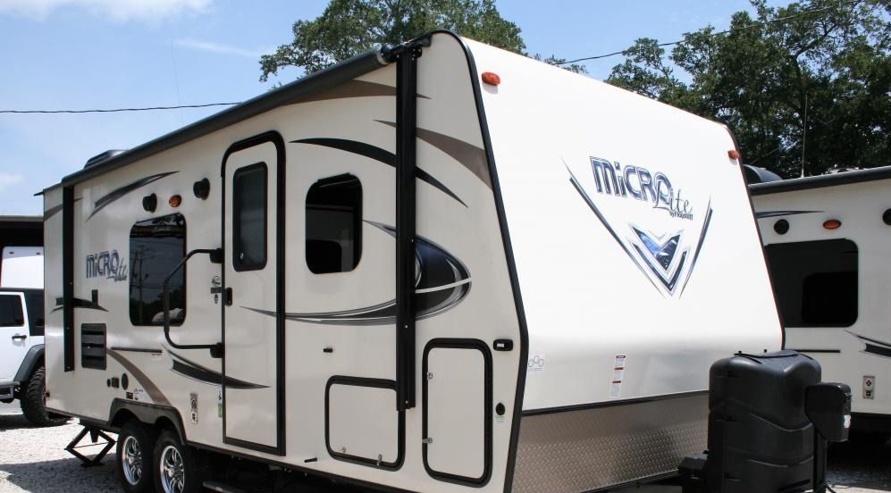 A large white RVs are parked in a grassy field