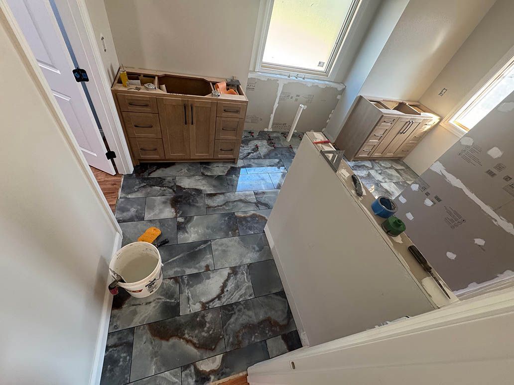 Bathroom with partially installed flooring, vanity, and shower. 