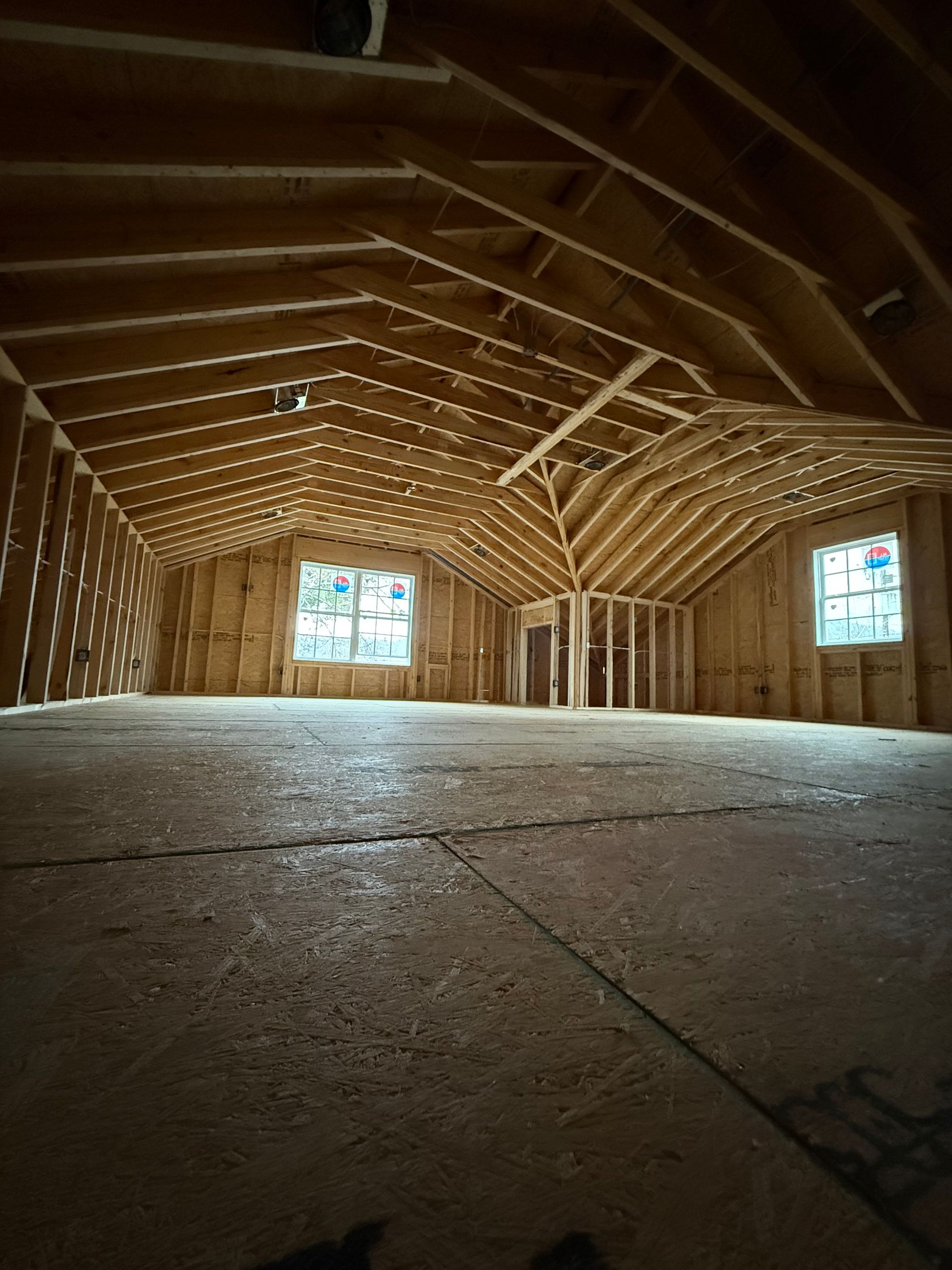 Interior of a building under construction. Wooden framing is visible, along with windows and a door frame.