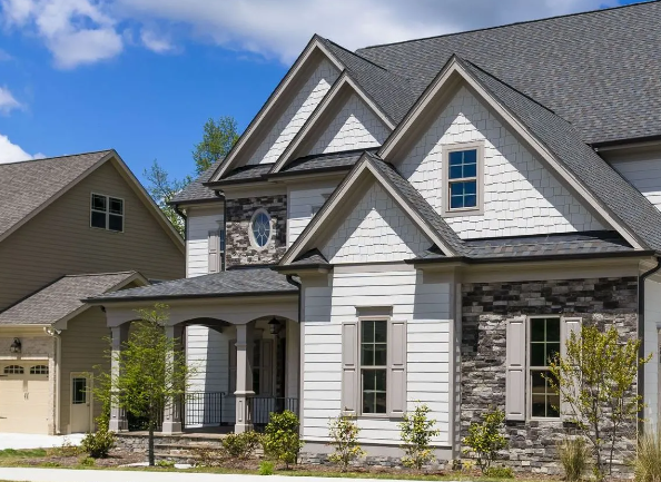 Two-story house with gray roof, white siding, stone accents, and small front porch.