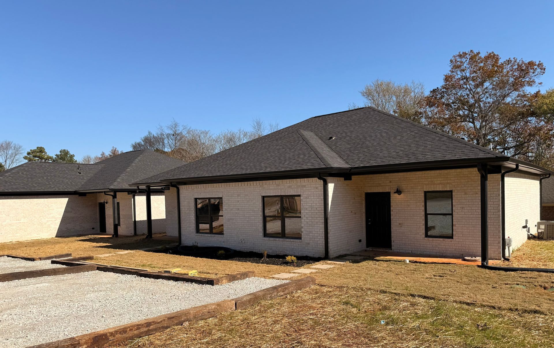 A row of newly constructed brick houses with black roofs and dark window frames.