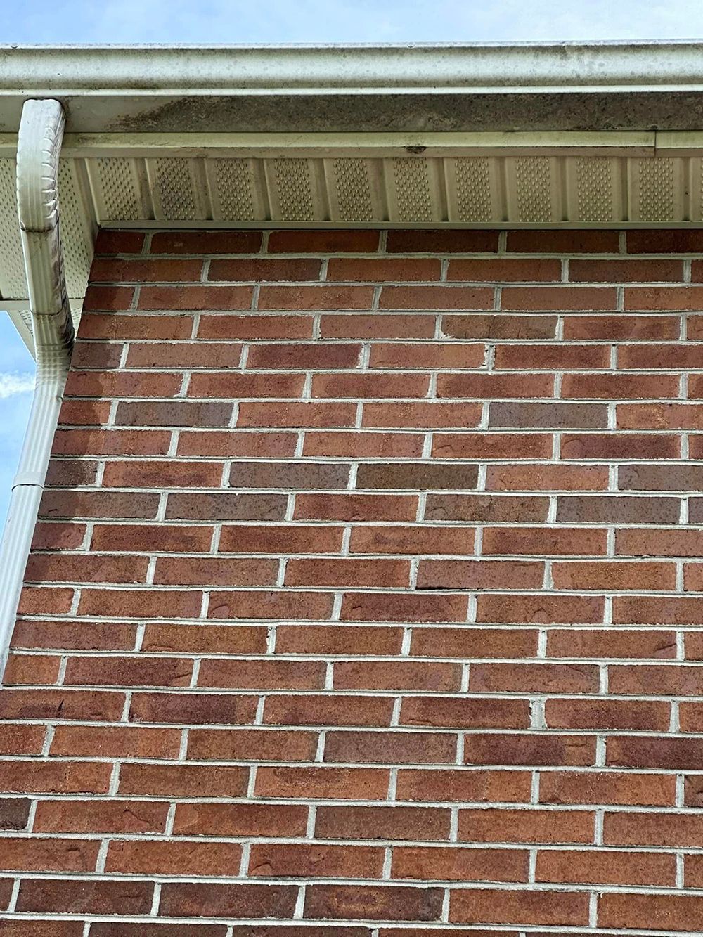 A close up of a brick wall with a white gutter on a house