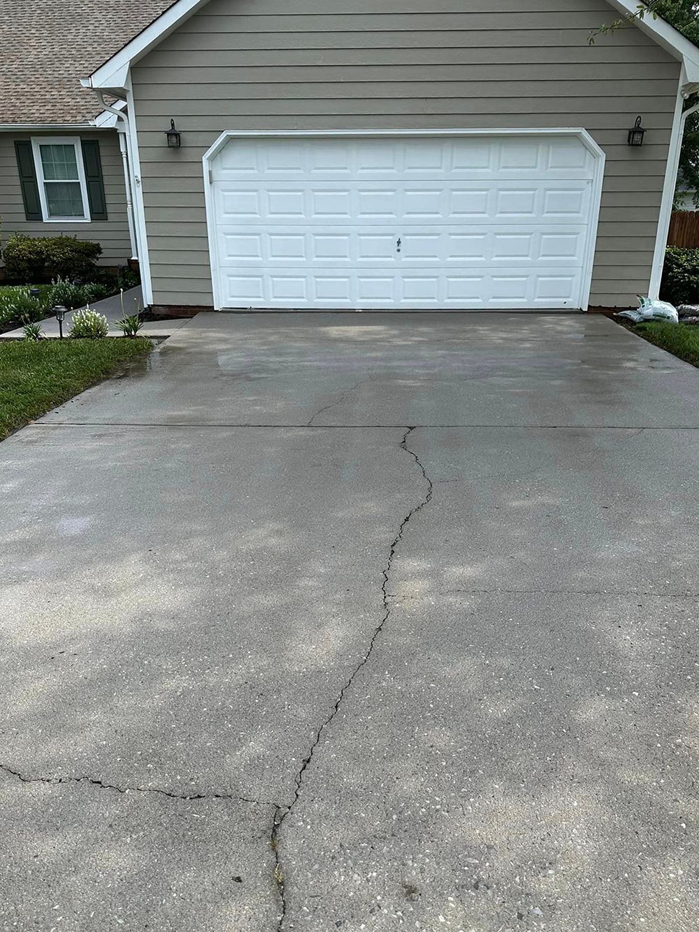 A concrete driveway in front of a house with a white garage door