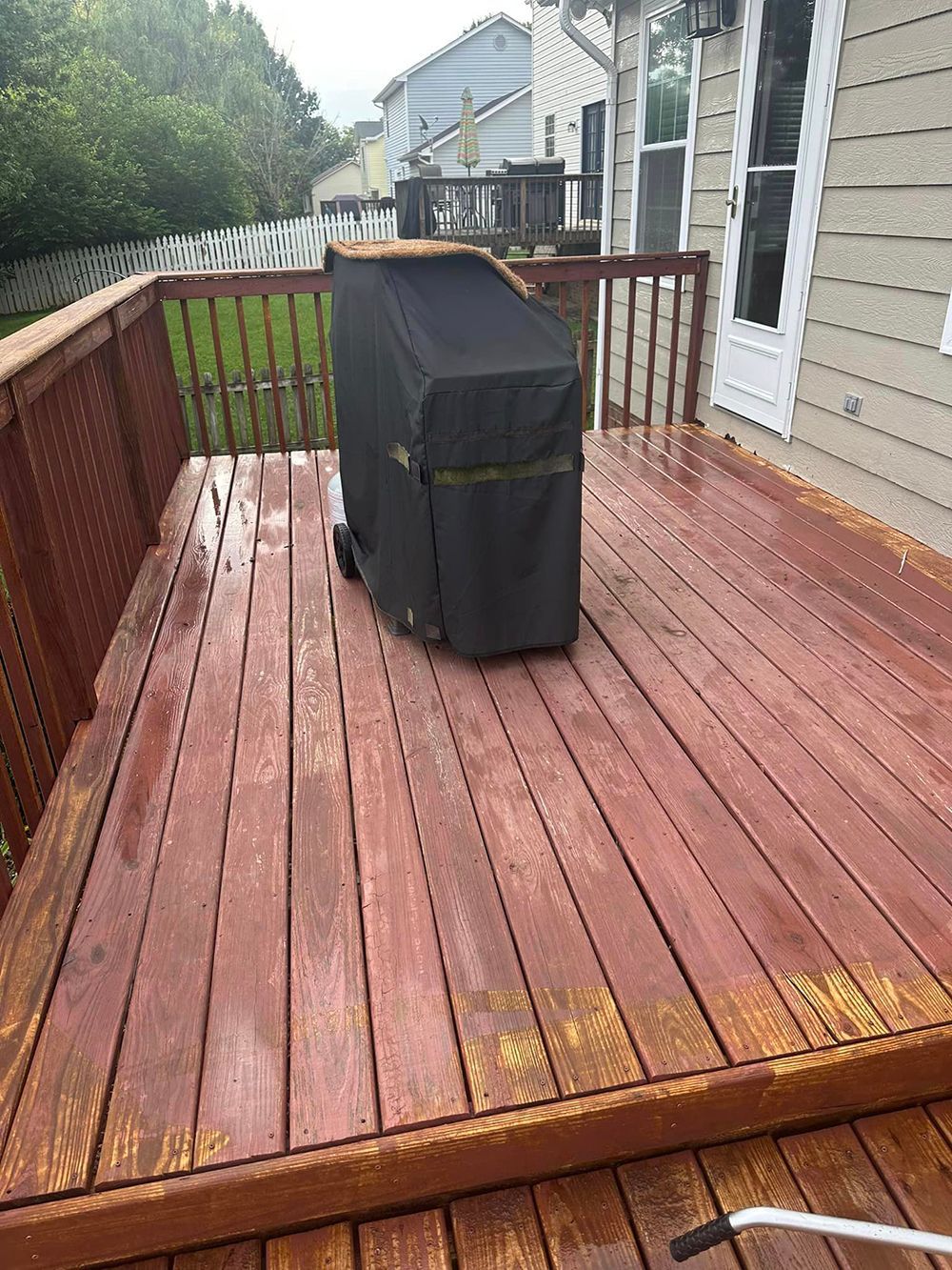 A wooden deck with a grill and a cover on it