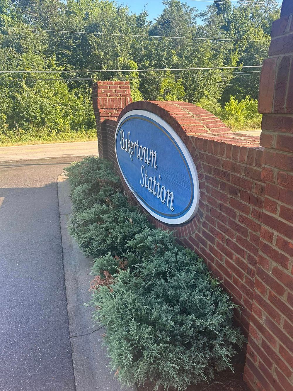 A blue sign on a brick wall next to a road