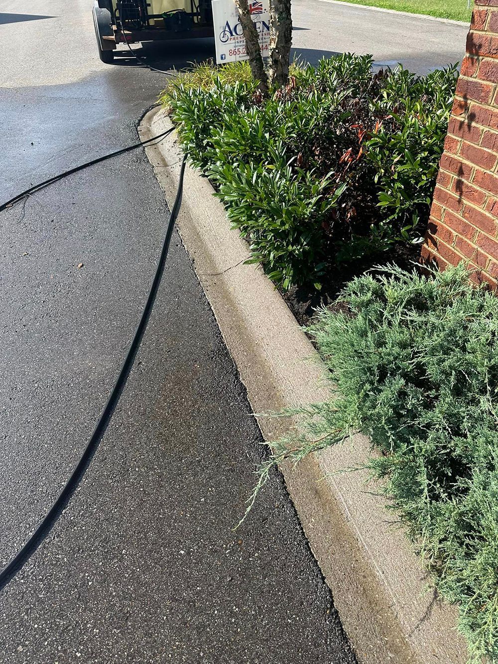 A hose is being used to clean a sidewalk next to a brick building