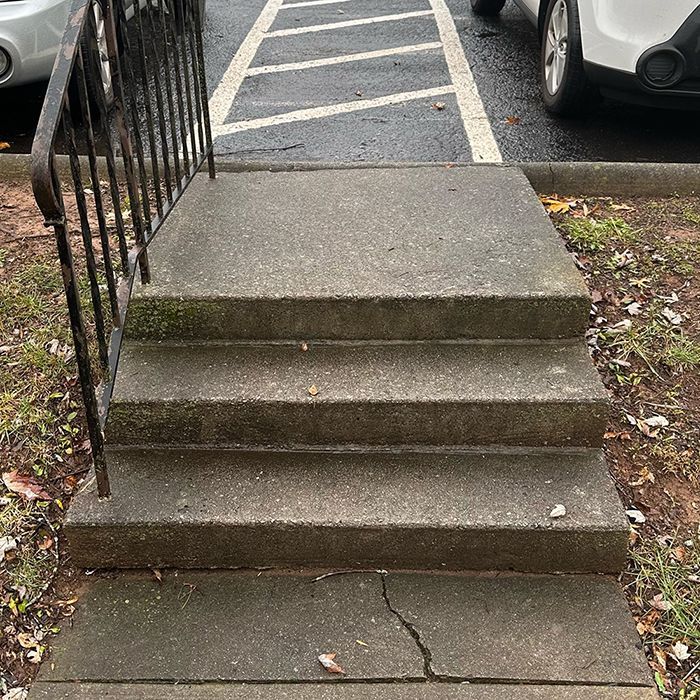 A set of concrete stairs leading up to a parking lot